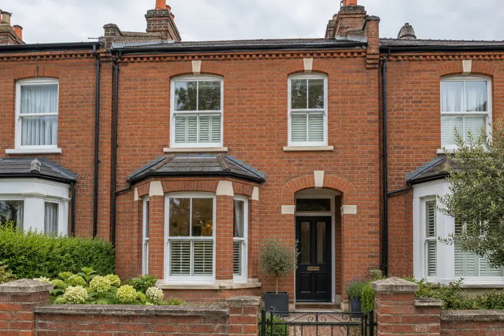AI-generated illustrative example: Front facade of a modest Victorian red brick British terrace home with carefully maintained repointed brickwork, natural window detailing, no numbers or signage