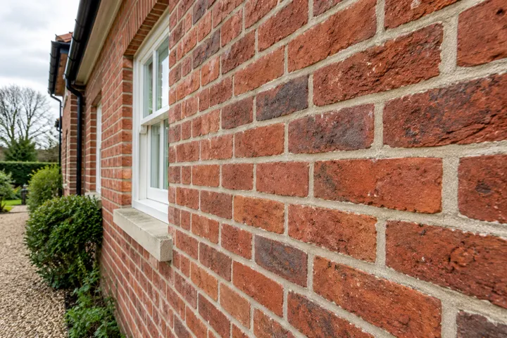 AI-generated illustrative example: Close-up of traditional red brickwork with neatly finished lime-coloured mortar joints, realistic brick texture and restrained mortar finish